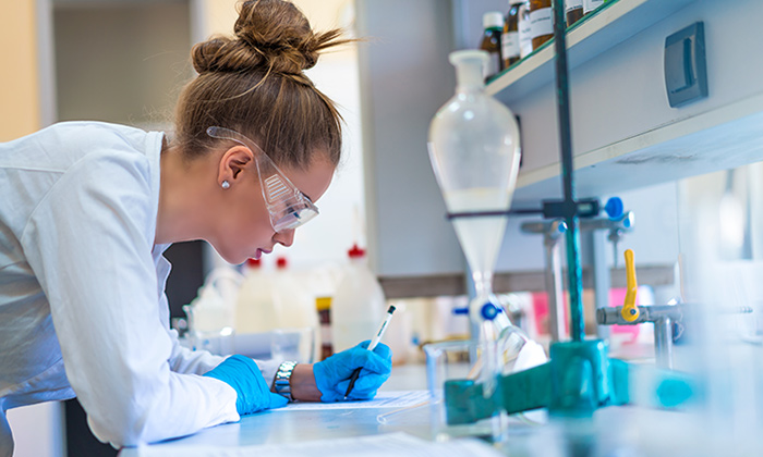 Femme avec blouse et gants dans un laboratoire industriel, faisant des essais